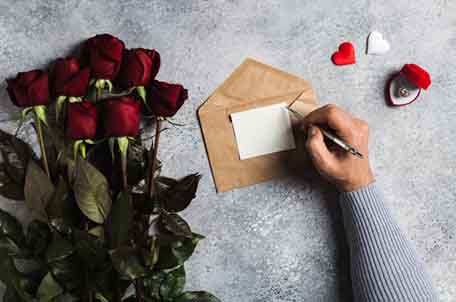 plan-the-perfect-valentines-day-man-hand-holding-pen-writing-love-letter-with-greeting-card